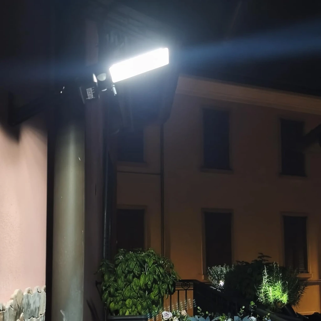 Foto de un cliente: el foco encendido encima de la puerta de casa, al anochecer, con las flores del balcón iluminadas