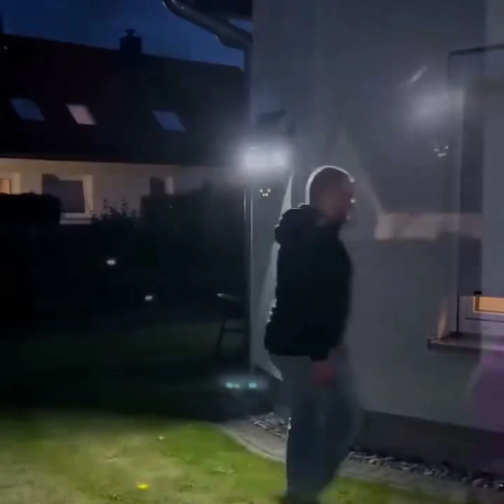 El hombre cruza el césped iluminado, grabado por la cámara de la pared